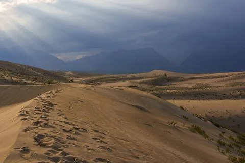 Dramatic desert dunes under sunbeams and cloudy sky Stock Photos