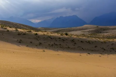 Dramatic desert dunes under sunbeams and cloudy sky Stock Photos