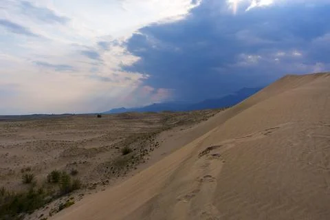 Dramatic desert dunes under sunbeams and cloudy sky Stock Photos