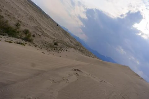 Dramatic desert dunes under sunbeams and cloudy sky Stock Photos
