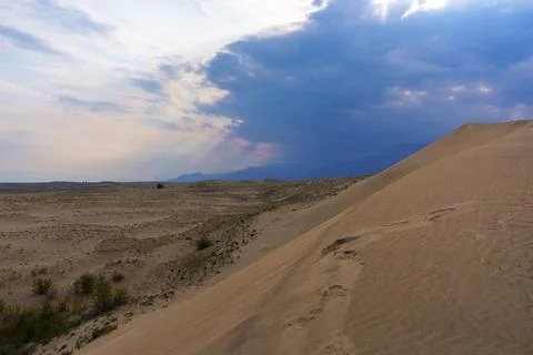 Dramatic desert dunes under sunbeams and cloudy sky Stock Photos