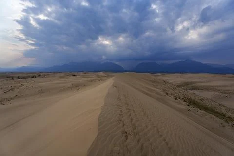 Dramatic desert dunes under sunbeams and cloudy sky Stock Photos