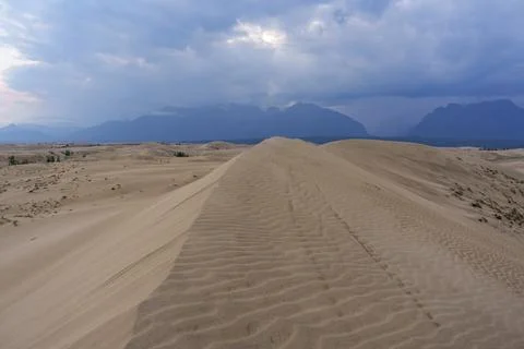 Dramatic desert dunes under sunbeams and cloudy sky Stock Photos