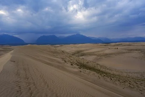 Dramatic desert dunes under sunbeams and cloudy sky Stock Photos