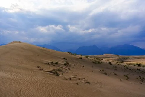 Dramatic desert dunes under sunbeams and cloudy sky Stock Photos