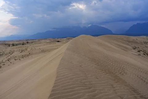 Dramatic desert dunes under sunbeams and cloudy sky Stock Photos