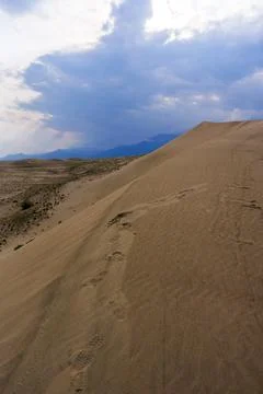 Dramatic desert dunes under sunbeams and cloudy sky Stock Photos