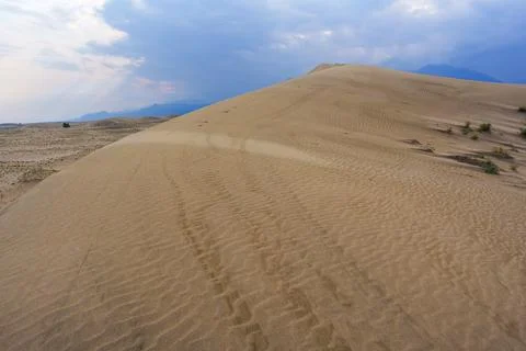 Dramatic desert dunes under sunbeams and cloudy sky Stock Photos