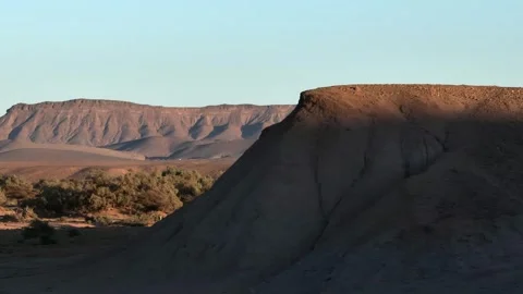 Dramatic Desert Landscape with Shadowed Mound and Eroded Plateau Stock Footage 336381196