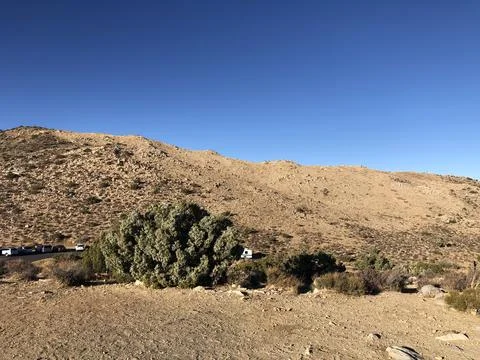 Dramatic Desert Landscape Under Bright Blue Sky With Rugged Hills Stock Photos