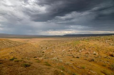Dramatic desert landscape under dark stormy clouds in arid region 스톡 사진