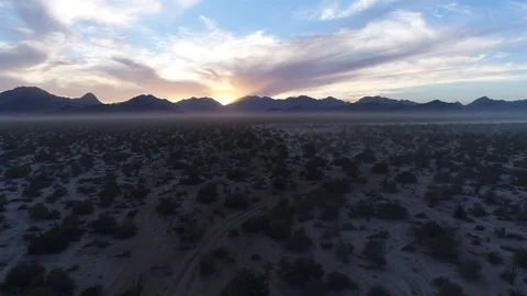Dramatic desert sunset with back lit mountains and haze drone Stock Footage 104884062