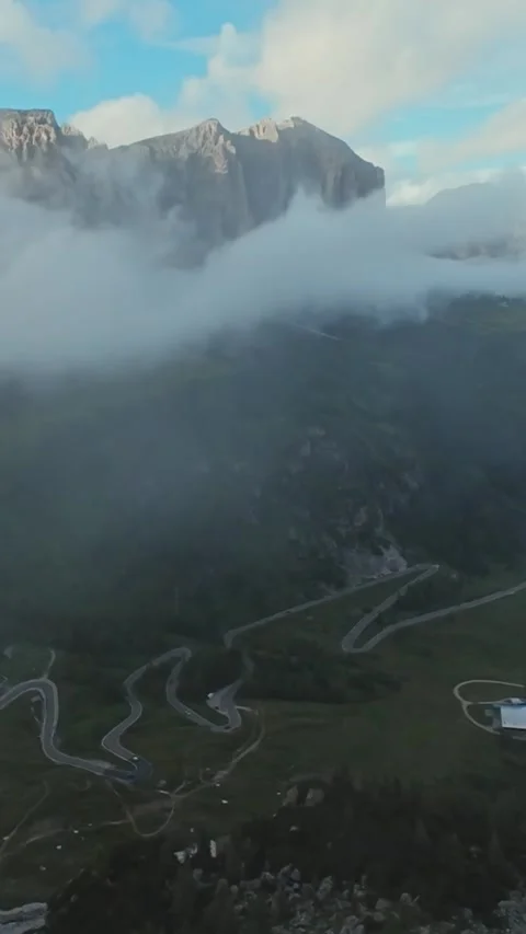 Dramatic dolomites peaks emerging through low clouds, sunlight brushing rugged Stockbeeldmateriaal 323890655