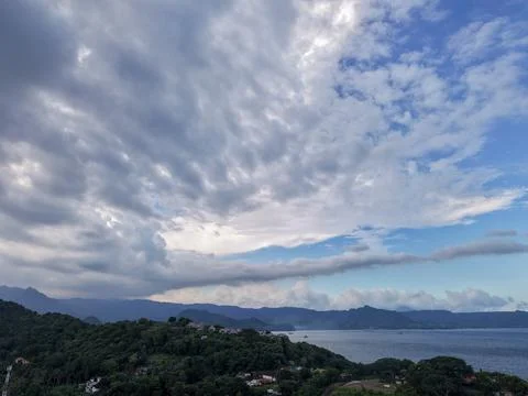 Dramatic dramatic cloudy sky over Padangbai coast and mountains in Bali 库存照片