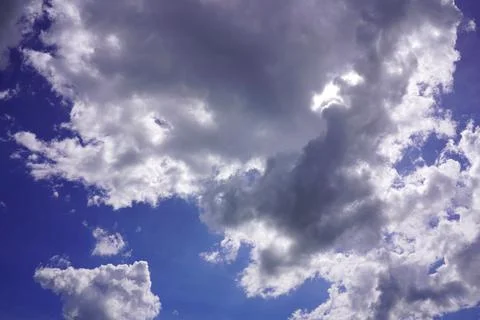 Dramatic dramatic white cumulus clouds on a vibrant blue summer sky backgroun Stock Photos