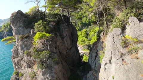 Dramatic Drone Flight Through Towering Rocky Cliffs into Turquoise Cove Stock Footage 315073723