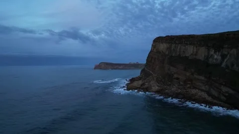 Dramatic drone flyby of coastal cliff and dark blue ocean at twilight Stock Footage 317447836