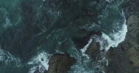 Dramatic drone photography of dark stones and white sea foam swirling in a .. Stock Footage 336927384