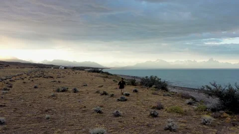 Dramatic drone scene of adventurer running alone on the shore of a glacier lake Stock Footage 255838954