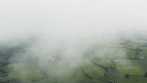 Dramatic Drone Shoot of Low Clouds Revealing Beautiful Green Fields Vídeo Stock 141645767