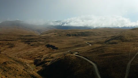 Dramatic drone shot of brown hills with empty winding roads Stock Footage 89516046
