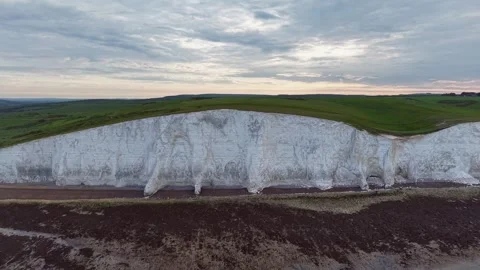 Dramatic drone tilt reveal of white cliff edge and green coastal hills Stock Footage 309764292