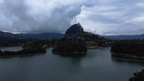 Dramatic Drone View of Piedra del Penol and Guatape Reservoir Under Storm Clouds Vídeos de archivo 345100850