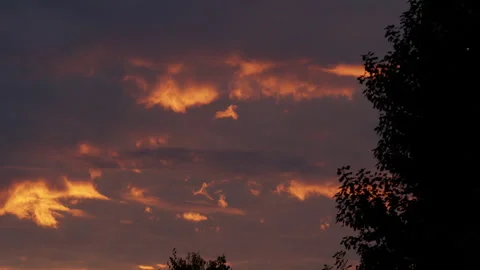 Dramatic dusk sky with glowing orange clouds drifting across a darkening horizon Video stock 317574360