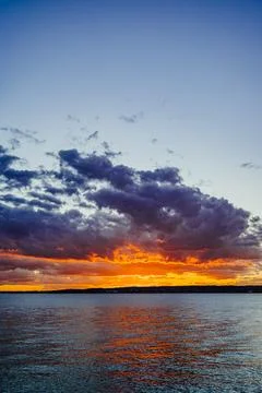 Dramatic evening sky above open water. Vertical view of heavy clouds glowin.. Stock Photos