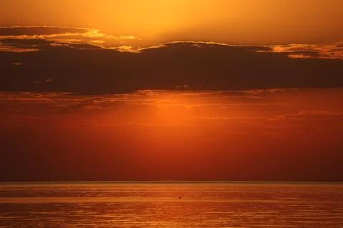 Dramatic evening sky over the sea. The setting sun is hidden behind heavy dark Stock Photos