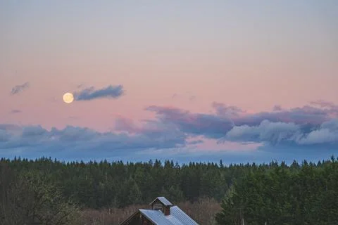 Dramatic Evening sky with yellow moon rising over County scene 写真素材