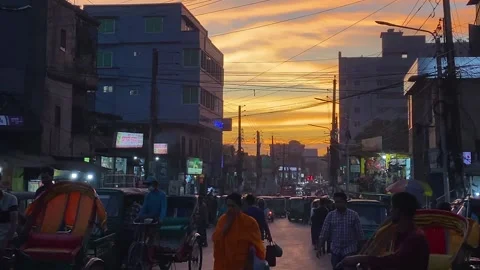 Dramatic evening view of a busy city street with golden sunset in Bangladesh Stock Footage 325832389