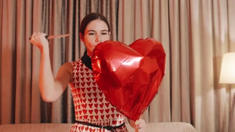 In a dramatic expression of heartbreak, a woman in a red dress cuts a heart Stock Footage 289792166