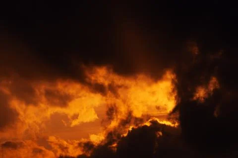 Dramatic fiery orange clouds at sunset time Stock Photos