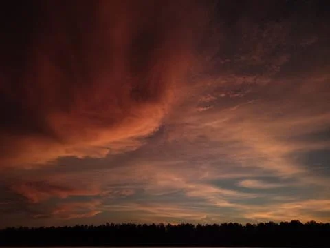 Dramatic Fiery Orange Clouds at Sunset Over Dark Forest Silhouette Stock Photos
