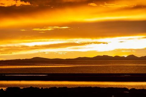 Dramatic Fiery Sunset Clouds Over Serene Lakeside Horizon Stock Photos