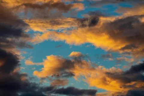 Dramatic fluffy clouds illuminated by disappearing rays at sunset and dark Stock Photos