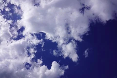 Dramatic fluffy white cumulus clouds moving across a deep blue vibrant summ.. Stock Photos