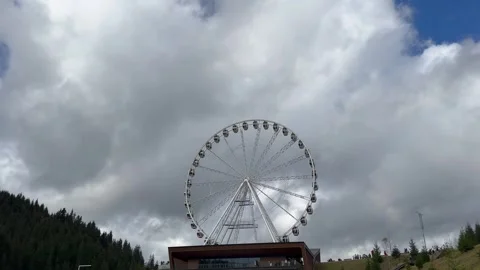 Dramatic giant ferris wheel spinning in scenic setting against cloudy sky Video stock 280008534