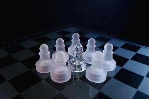 Dramatic glass chess set with white lighting symbolizing abuse, oppression and i Stock-Fotos