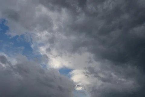 Dramatic gloomy sky densely covered with dark storm clouds with small patch.. 스톡 사진