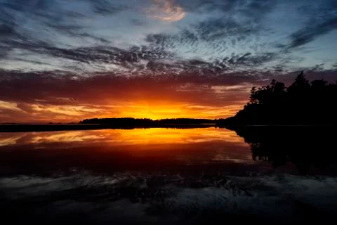Dramatic Glowing Cloud Reflected In The Tranquil Ocean Water At Sunset With A Si Stockfoto's