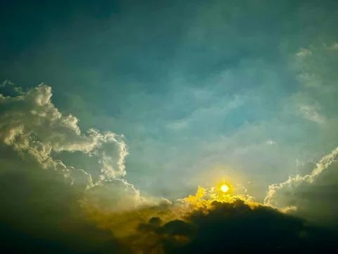 Dramatic Glowing Sun Rising Behind Mountain Clouds with Teal Sky and Copy Space Stock Photos