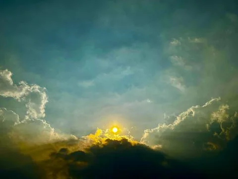 Dramatic Glowing Sun Rising Behind Mountain Clouds with Teal Sky and Copy Space Stock Photos