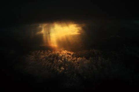 Dramatic god light rays shining from dark cloud on to clouds expanse on the s Stock Photos