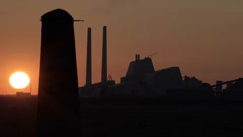 Dramatic golden red sunset behind fossil fuel burning power plant silhouette  Stock Footage 107051070