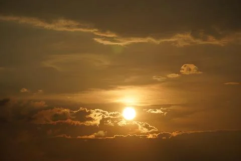 Dramatic golden sunrise over cloudy horizon with warm glowing sunlight rays i Stock Photos
