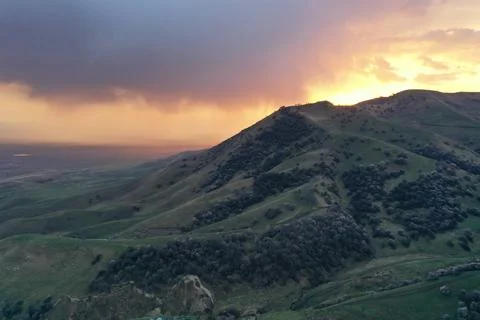 Dramatic Golden Sunset Behind Green Hill with Stormy Sky and Rain, Xinjiang.. Stock Photos