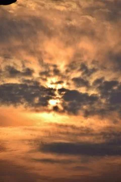 Dramatic golden sunset behind textured clouds Stock Photos