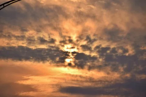 Dramatic golden sunset behind textured clouds Stock Photos